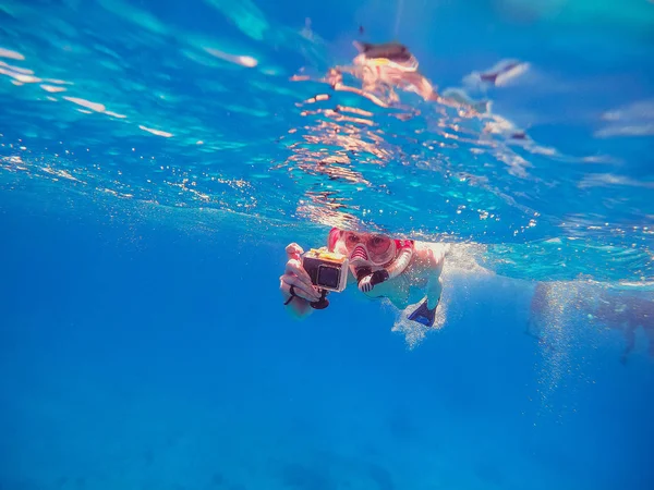 Snorkeling Menina com uma câmera de ação flutua no mar e shoo — Fotografia de Stock