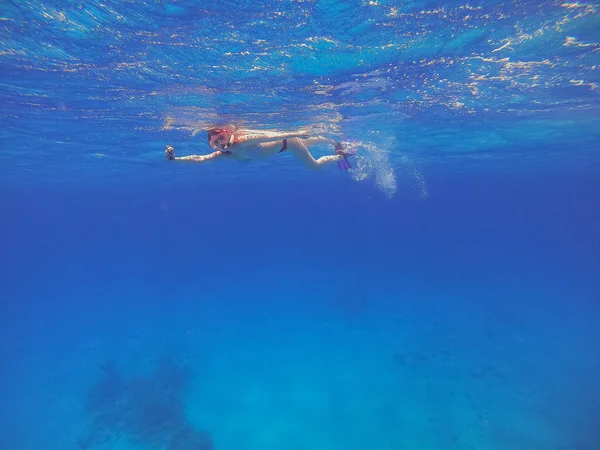Snorkeling Girl with an action camera floats in the sea and shoo