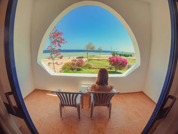 Window overlooking the sea. The girl goes to the loggia and look