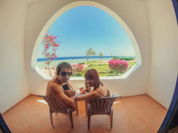 Window overlooking the sea. The guy and the girl are sitting on