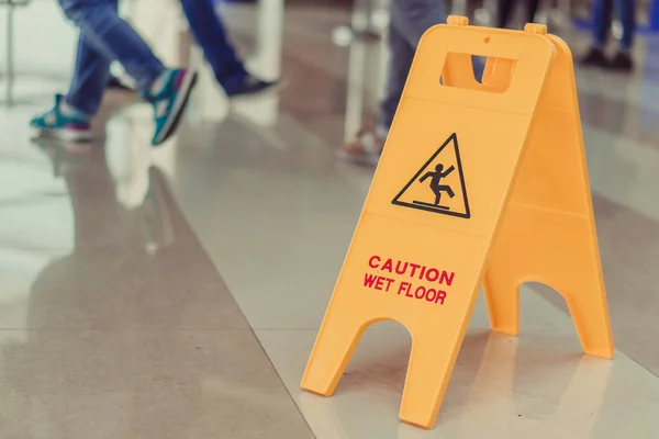 La placa es suelo mojado. La gente camina sobre el suelo mojado . —  Fotos de Stock