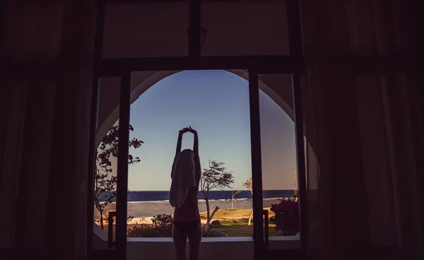Window overlooking the sea. The girl goes to the loggia and look