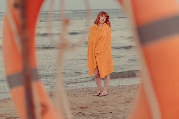 Lifebuoy. Девушка в теплом полотенце стоит у моря — стоковое фото