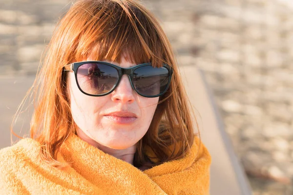 Una ragazza in occhiali da sole sta guardando il mare, silhouette di persone — Foto Stock