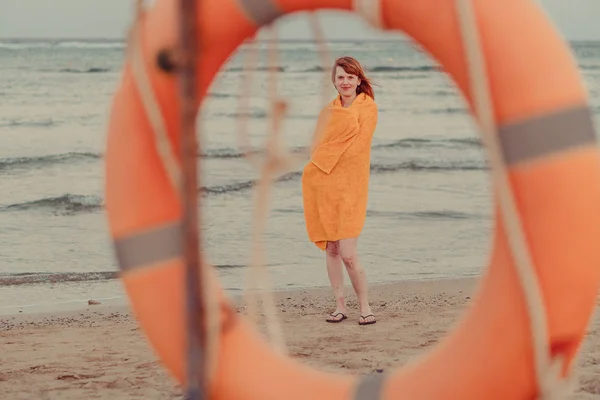Lifebuoy. Девушка в теплом полотенце стоит у моря — стоковое фото