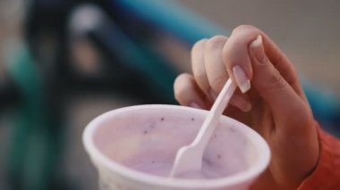 Yoğurt. Kız plastik bir bardaktan plastik kaşık yoğurt yiyor..