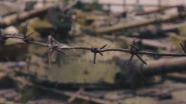 Mezarlık askeri teçhizatı. Dikenli tel depo paslı tankları altında