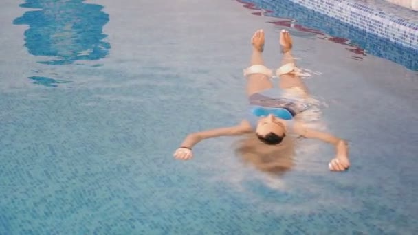 プール プールの水の上に彼女の背中に横たわっている女の子 — ストック動画