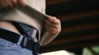 Tabanca. Adam giysilerinin altına silah saklıyor.