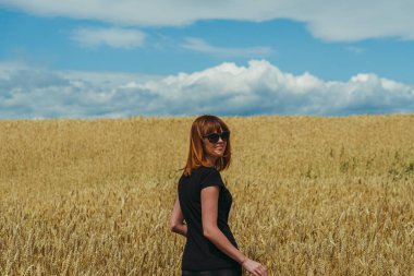 Alan. Bir kız sarı buğday tarlasında yürüyor..