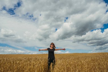 Alan. Bir kız sarı buğday tarlasında yürüyor..