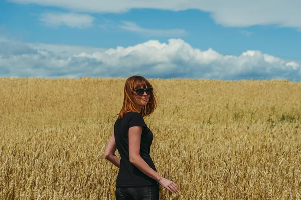 Campo. Uma menina caminha através de um campo de trigo amarelo . — Fotografia de Stock