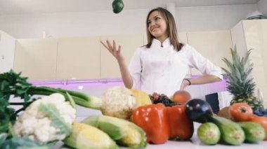 Sebzeli mutfak. Bir kız mutfakta duruyor ve elinde bir avokado tutar.