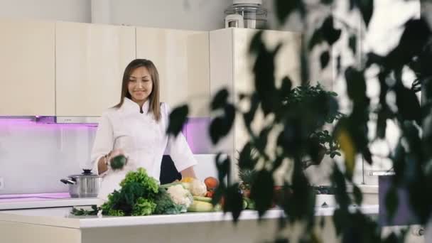 野菜付きのキッチン 女の子は台所に立って 彼女の手にアボカドを保持します — ストック動画