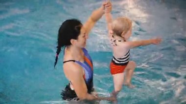 Yüzme havuzu. Annem küçük bir çocuğa havuzda yüzmeyi öğretiyor..