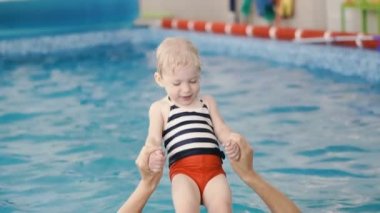 Yüzme havuzu. Annem küçük bir çocuğa havuzda yüzmeyi öğretiyor..