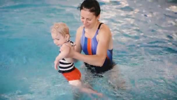 プール ママはプールで泳ぐために幼い子供を教えます — ストック動画