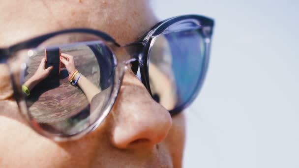 Handy Eine Frau Mit Sonnenbrille Blickt Auf Ein Handy — Stockvideo