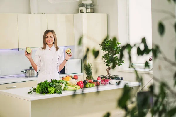 Cocina con verduras. Una chica se para en la cocina y sostiene — Foto de Stock