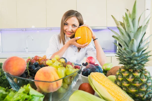 Melón. Una mujer en la cocina sostiene un melón en sus manos . — Foto de Stock