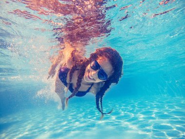 Yüzme havuzu. Bir kadın güneş gözlüğü yle havuzda yüzüyor..