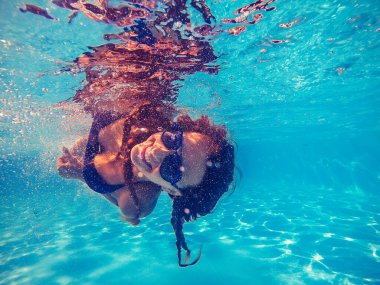 Yüzme havuzu. Bir kadın güneş gözlüğü yle havuzda yüzüyor..