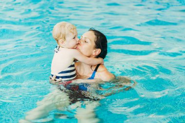 Yüzme havuzu. Annem küçük bir çocuğa havuzda yüzmeyi öğretiyor..