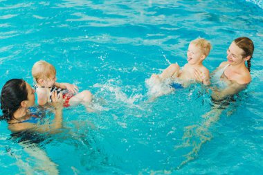 Yüzme havuzu. Anneler küçük çocuklara yüzmeyi öğretir..