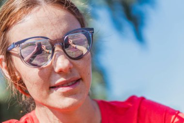 Cep telefonu. Güneş gözlüğü takan bir kadın cep telefonuna bakıyor..