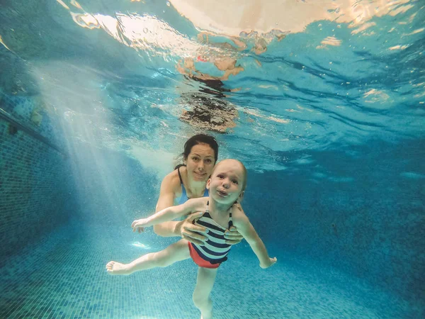 Zwembad. Moeder duikt met haar baby onder het zwembad water. — Stockfoto