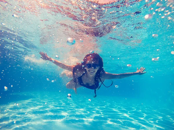 Piscina. Una mujer nada en la piscina con gafas de sol . — Foto de Stock