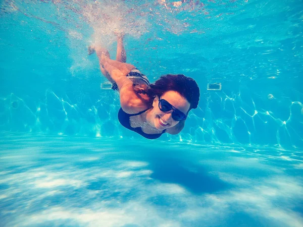 Piscina. Una mujer nada en la piscina con gafas de sol . — Foto de Stock