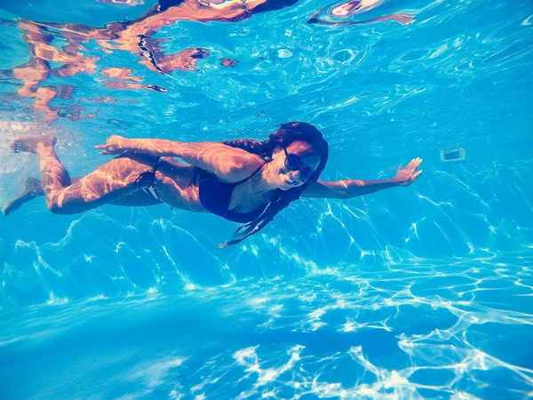 Piscina. Una mujer nada en la piscina con gafas de sol . — Foto de Stock