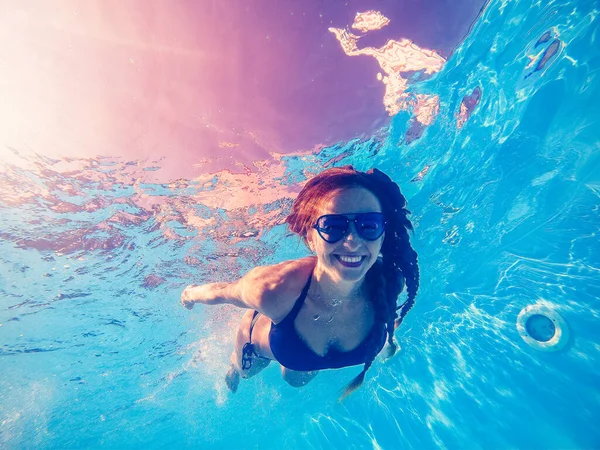 Schwimmbad. Eine Frau schwimmt mit Sonnenbrille im Pool. — Stockfoto