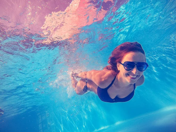 游泳池。一个女人戴着太阳镜在游泳池里游泳. — 图库照片