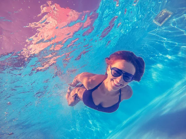 Piscina. Una mujer nada en la piscina con gafas de sol . —  Fotos de Stock