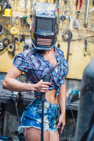 Chica soldadora. Una chica con una máquina de soldadura suelda metal . — Foto de Stock