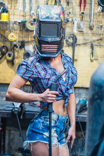 Chica soldadora. Una chica con una máquina de soldadura suelda metal . — Foto de Stock