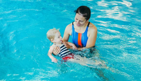 Piscina. Mamma insegna a un bambino a nuotare in piscina . — Foto Stock