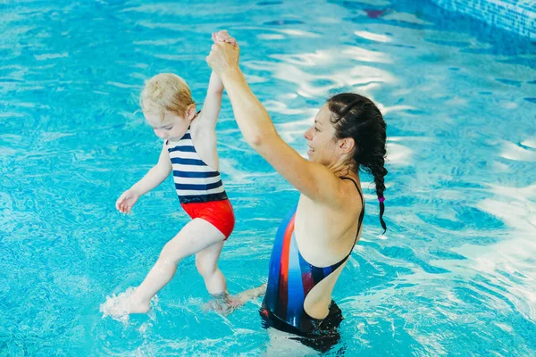 Бассейн. Мама учит маленького ребенка плавать в бассейне . — стоковое фото