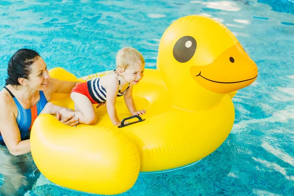 Piscina. Mamá enseña a un niño pequeño a nadar en la piscina . — Foto de Stock