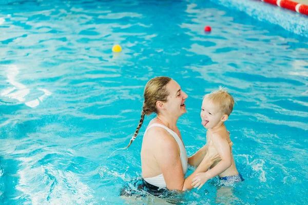 Бассейн. Мама учит маленького ребенка плавать в бассейне . — стоковое фото