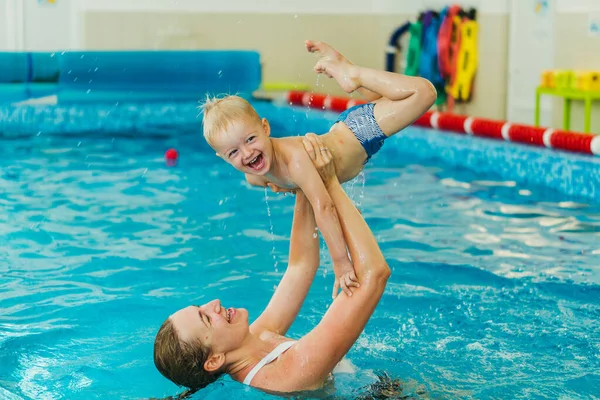 Piscina. Mamá enseña a un niño pequeño a nadar en la piscina . — Foto de Stock