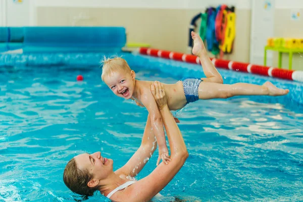 Piscina. Mamá enseña a un niño pequeño a nadar en la piscina . — Foto de Stock