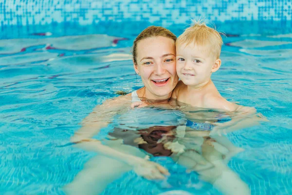 Piscina. Mamá enseña a un niño pequeño a nadar en la piscina . — Foto de Stock