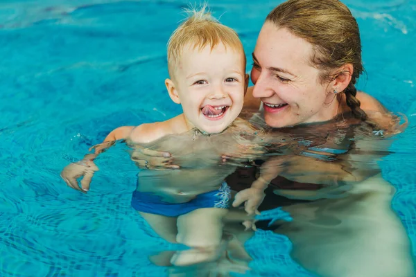 Swimming pool. Mom teaches a young child to swim in the pool.