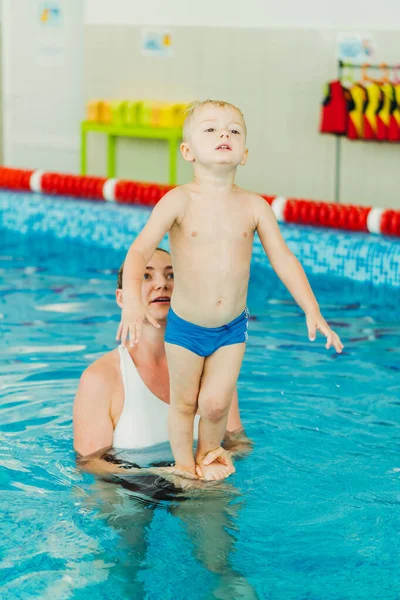 Piscina. Mamá enseña a un niño pequeño a nadar en la piscina . — Foto de Stock