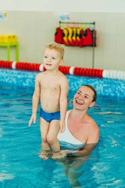 Piscina. Mamá enseña a un niño pequeño a nadar en la piscina . — Foto de Stock
