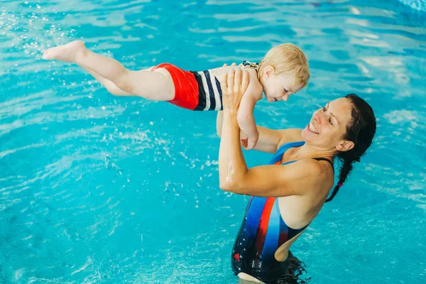 Piscina. Mamá enseña a un niño pequeño a nadar en la piscina . — Foto de Stock