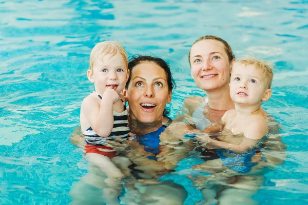 Piscina. Las mamás enseñan a los niños pequeños a nadar . — Foto de Stock